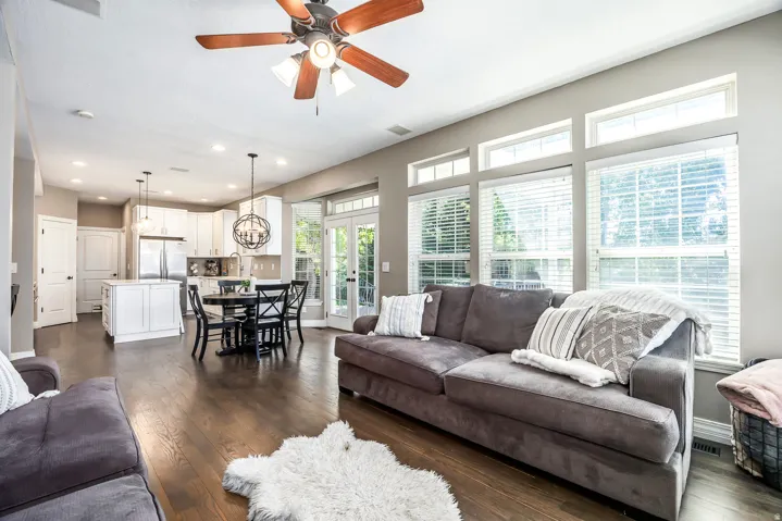 Living room featuring dark wood-style floors, french doors, a ceiling fan, and a chandelier