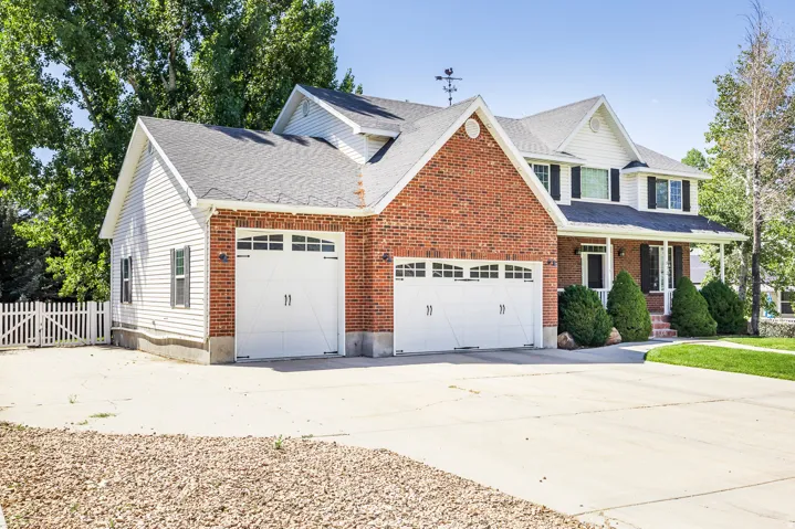 Traditional-style home featuring driveway, a porch, brick siding, and a shingled roof