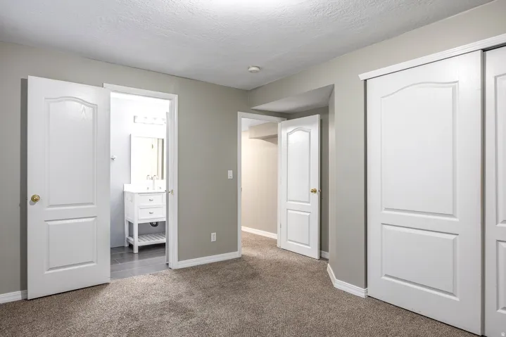 Unfurnished bedroom featuring carpet, a closet, ensuite bathroom, and a textured ceiling