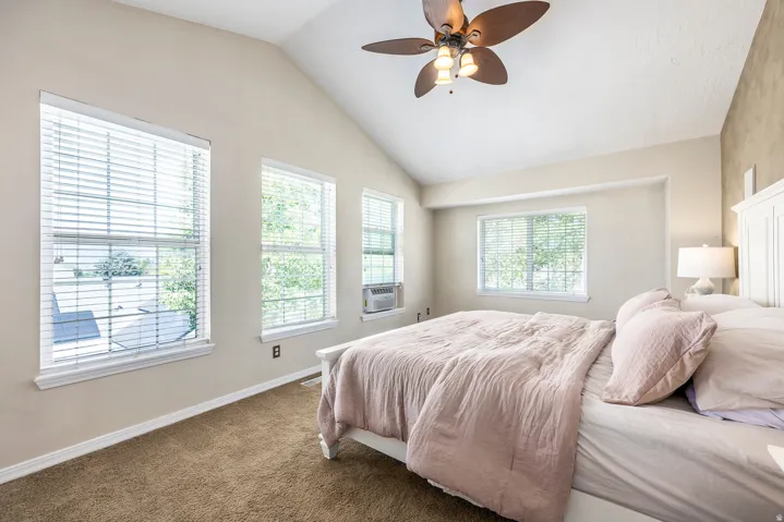 Carpeted bedroom featuring lofted ceiling, ceiling fan, and cooling unit