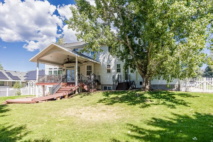 Back of house with a fenced backyard, ceiling fan, a wooden deck, and a gate