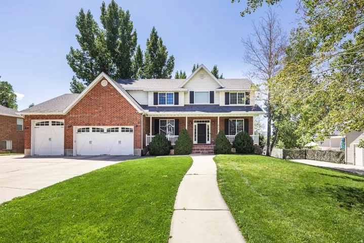 Traditional home featuring a porch, a front lawn, brick siding, and concrete driveway