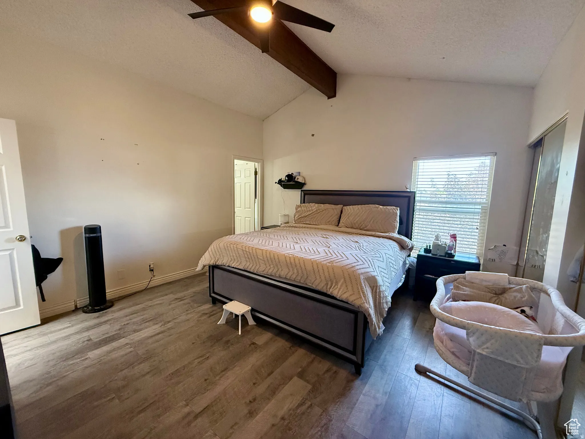 Bedroom with a textured ceiling, beam ceiling, wood finished floors, a ceiling fan, and a closet