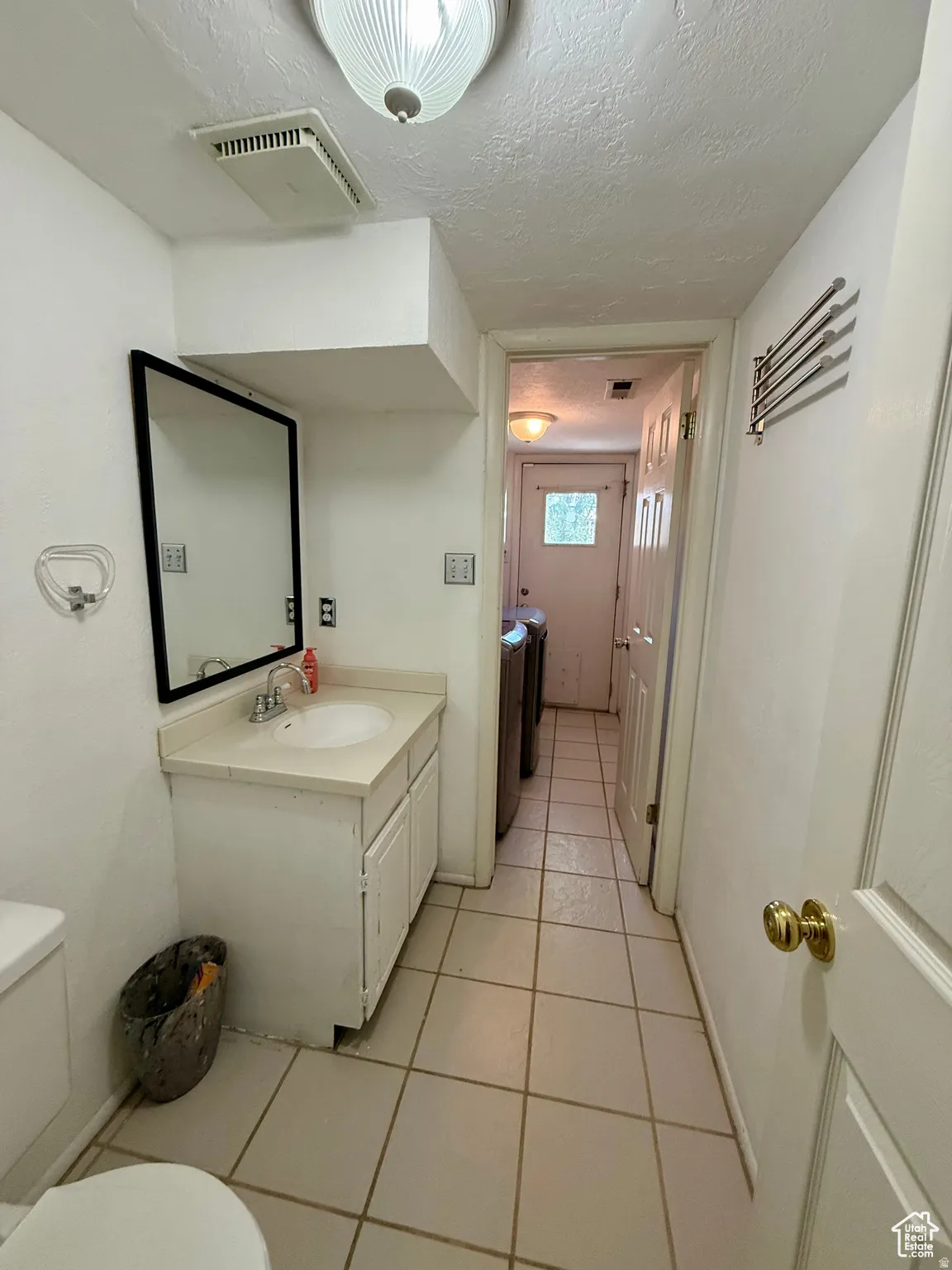 Bathroom featuring a textured ceiling, vanity, and light tile patterned floors