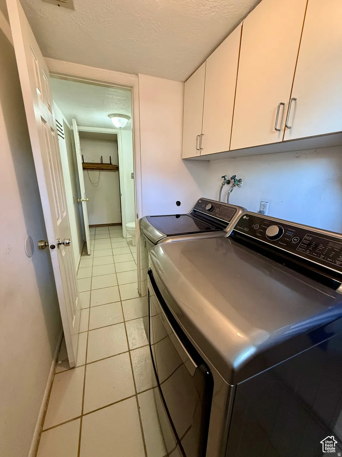 Laundry area featuring cabinet space, a textured ceiling, and washer and dryer