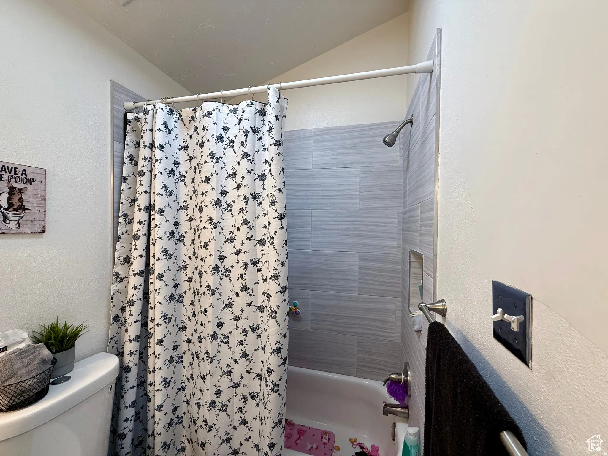 Full bath featuring shower / bathtub combination with curtain and a textured wall