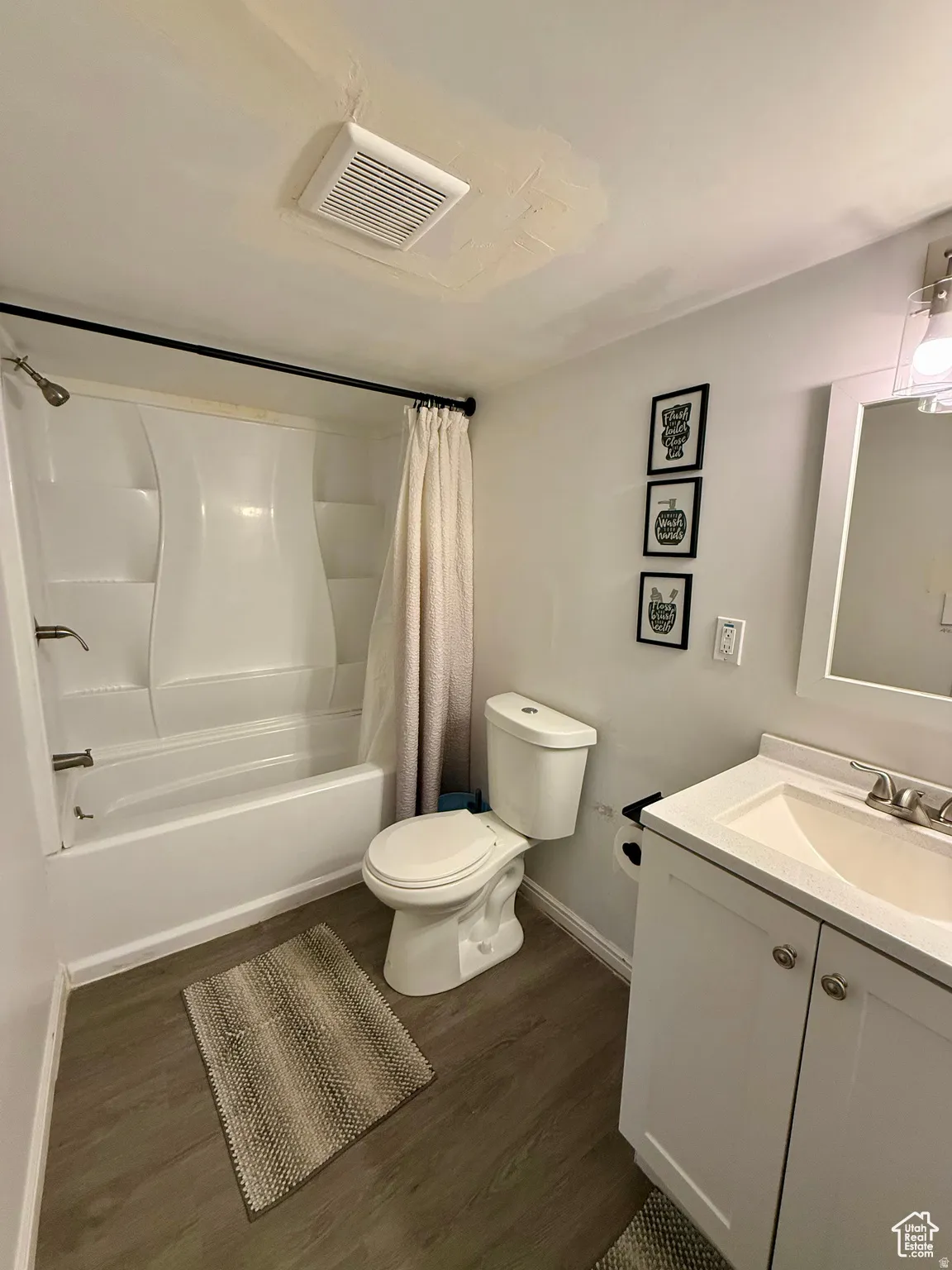 Bathroom with vanity, shower / bath combo with shower curtain, and dark wood-style floors