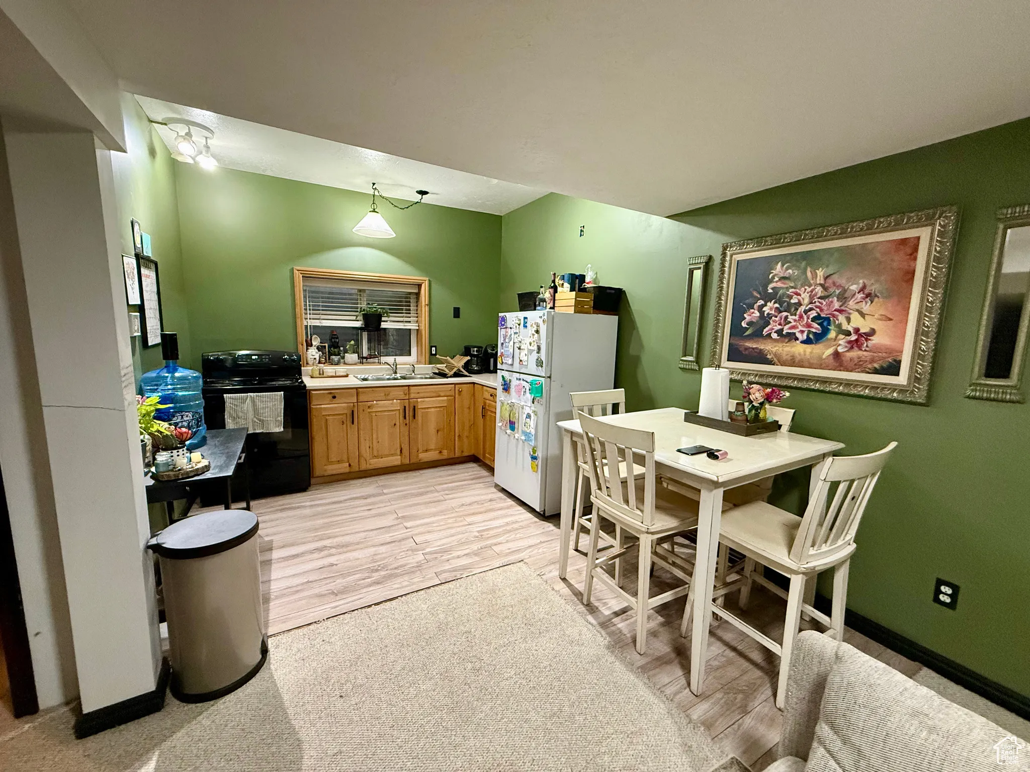 Kitchen featuring freestanding refrigerator, electric range, light wood-type flooring, light countertops, and wood finish cabinetry