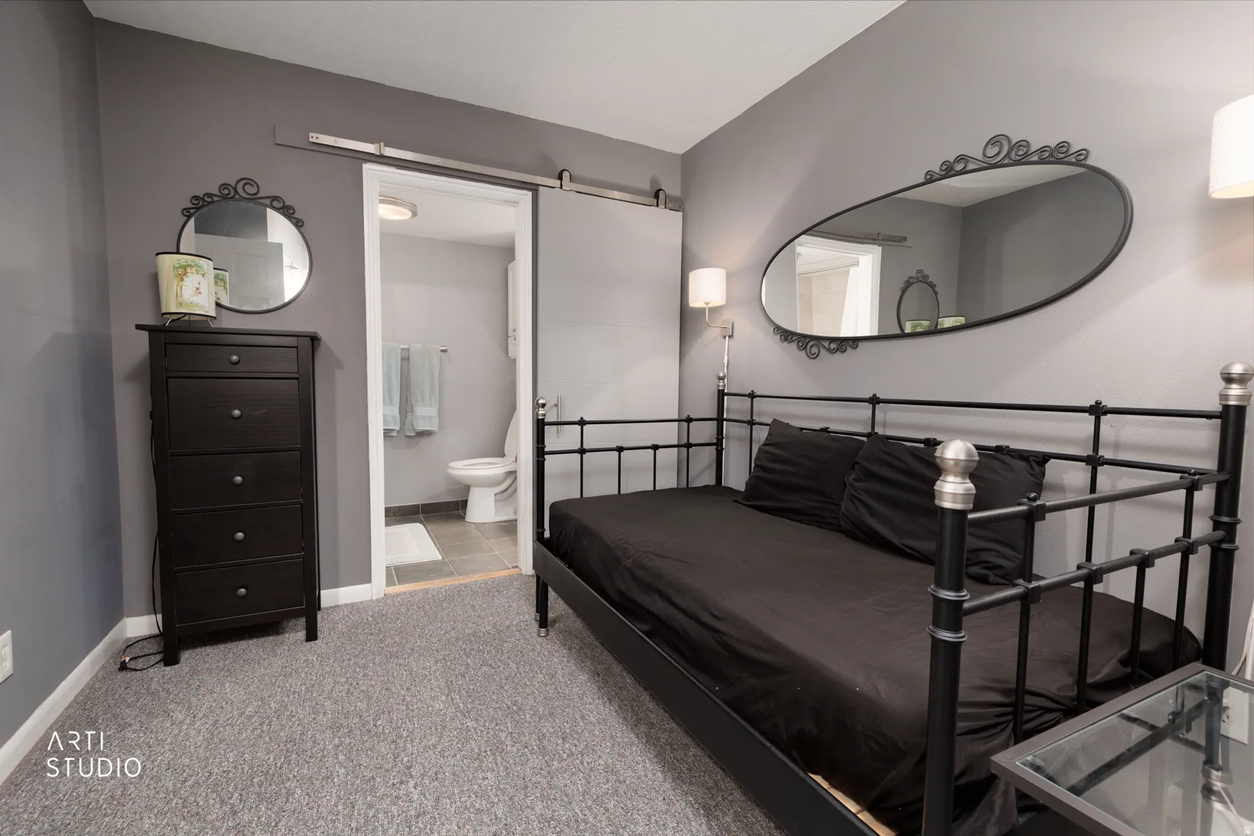 Bedroom featuring a barn door, light carpet, and ensuite bath