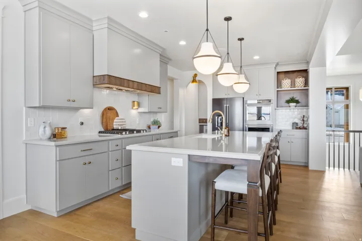 Kitchen featuring a center island with sink, decorative light fixtures, a breakfast bar, decorative backsplash, and light wood finished floors