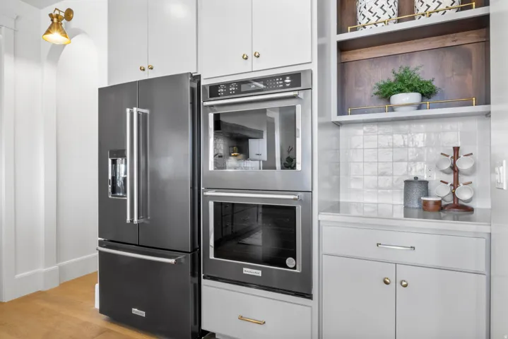 Kitchen featuring stainless steel appliances, white cabinets, open shelves, light countertops, and light wood-style flooring