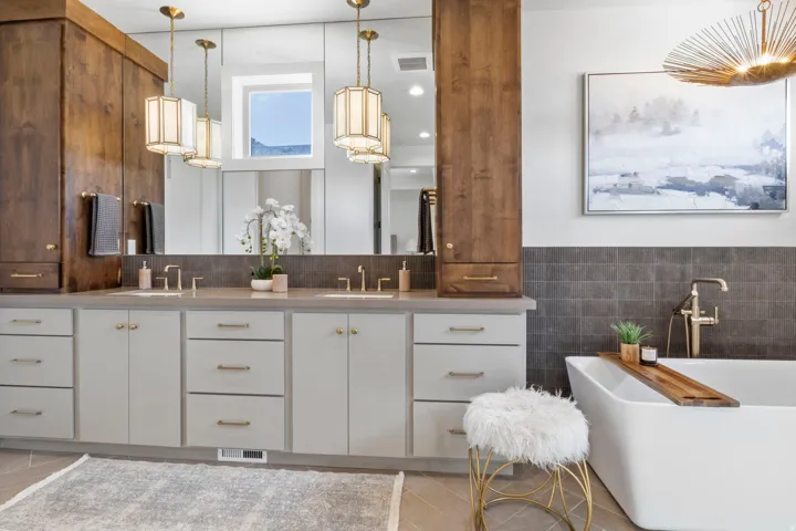 Full bath featuring double vanity, a freestanding tub, tile walls, light tile patterned floors, and wainscoting