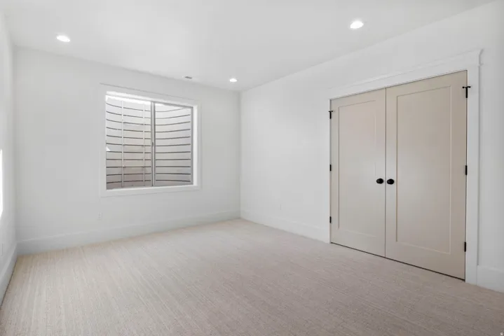 Unfurnished bedroom with light colored carpet, a closet, and recessed lighting