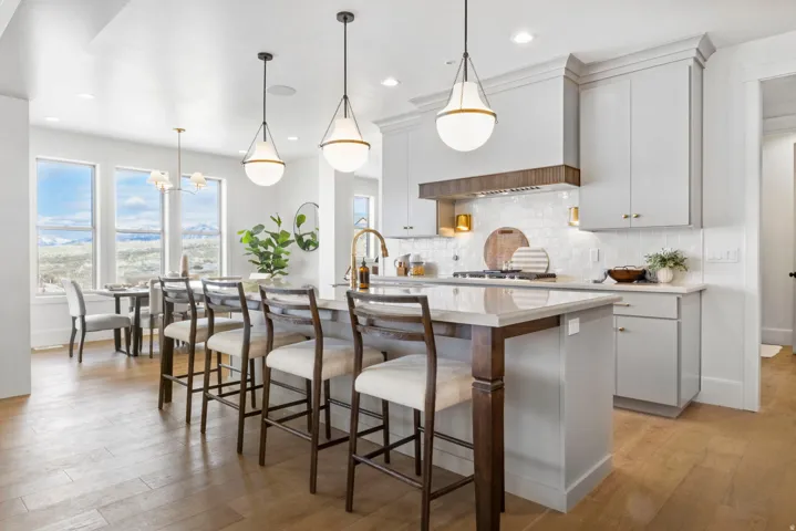 Kitchen with a center island with sink, a kitchen bar, light wood-type flooring, light stone countertops, and hanging lights