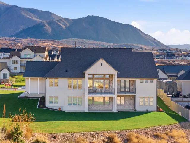 Back of house featuring a balcony, a mountain view, a patio, board and batten siding, and a lawn