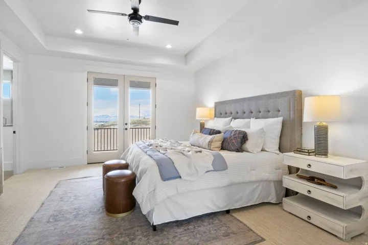 Bedroom featuring access to outside, a tray ceiling, french doors, ceiling fan, and carpet floors