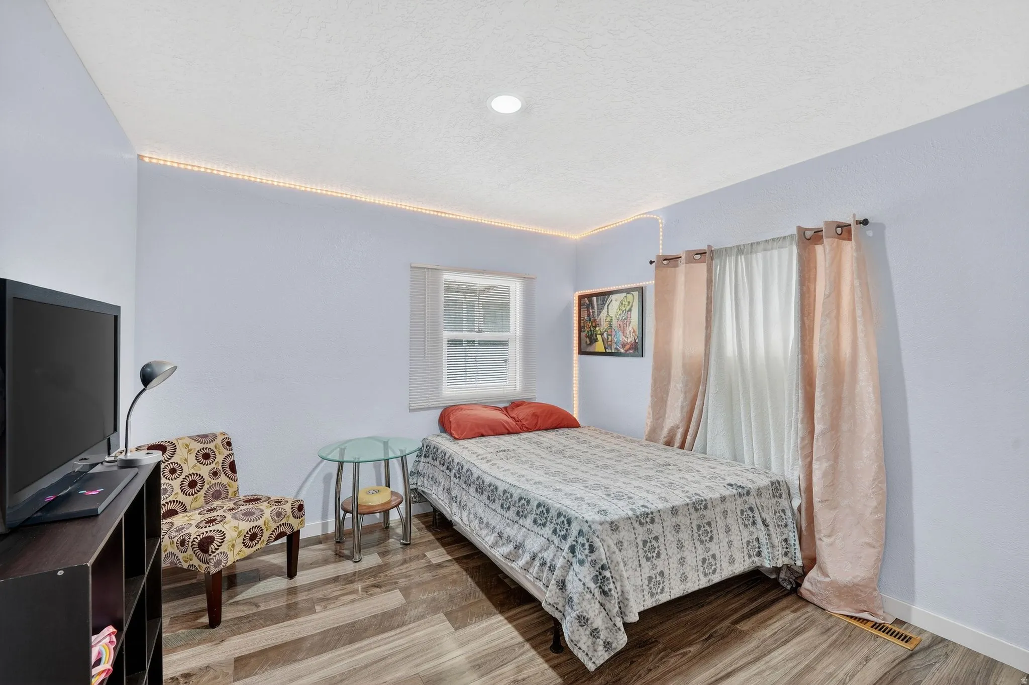Bedroom with wood finished floors and a textured ceiling