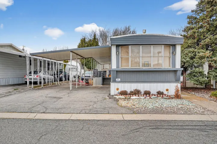 Manufactured / mobile home with a carport and asphalt driveway