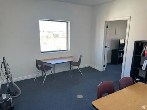 Home office with dark carpet and baseboards