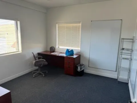 Office space featuring dark colored carpet and baseboards