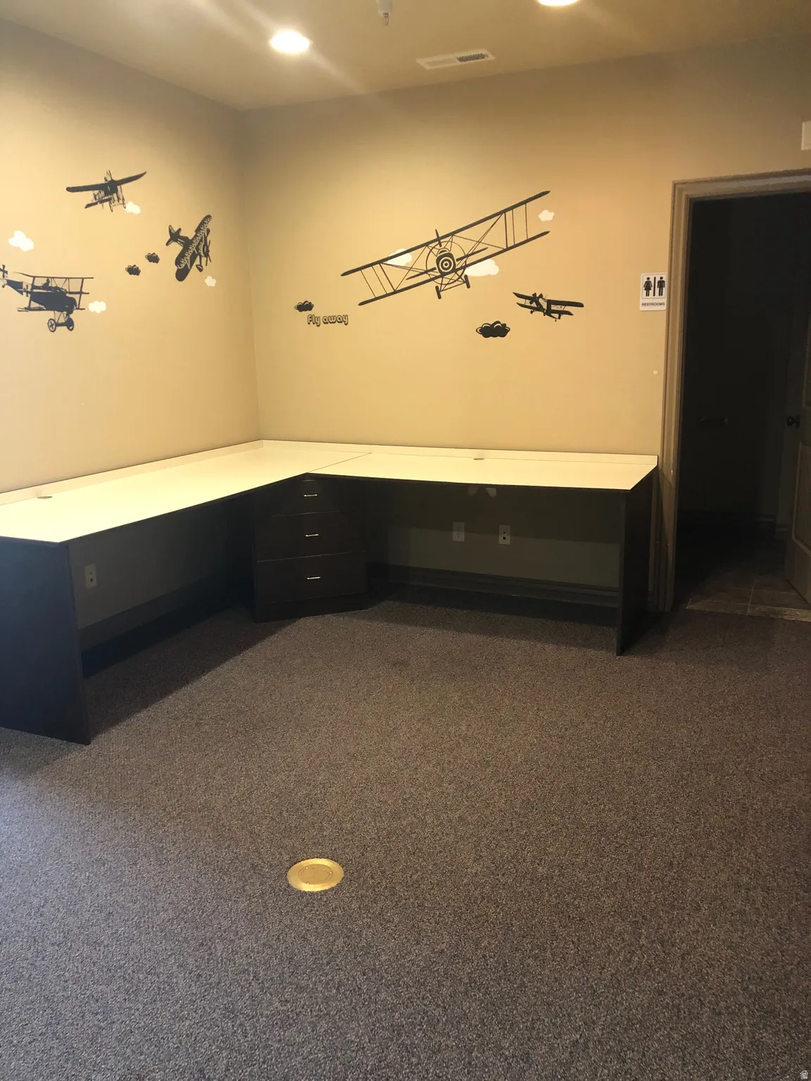 Unfurnished office featuring built in desk and dark carpet