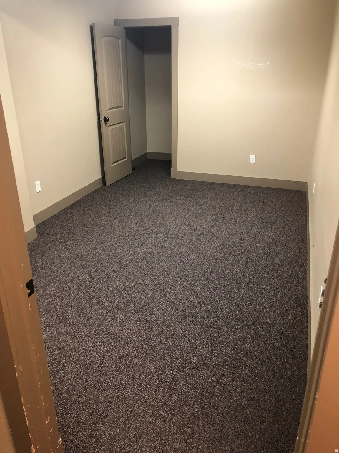 Empty room with dark carpet and baseboards