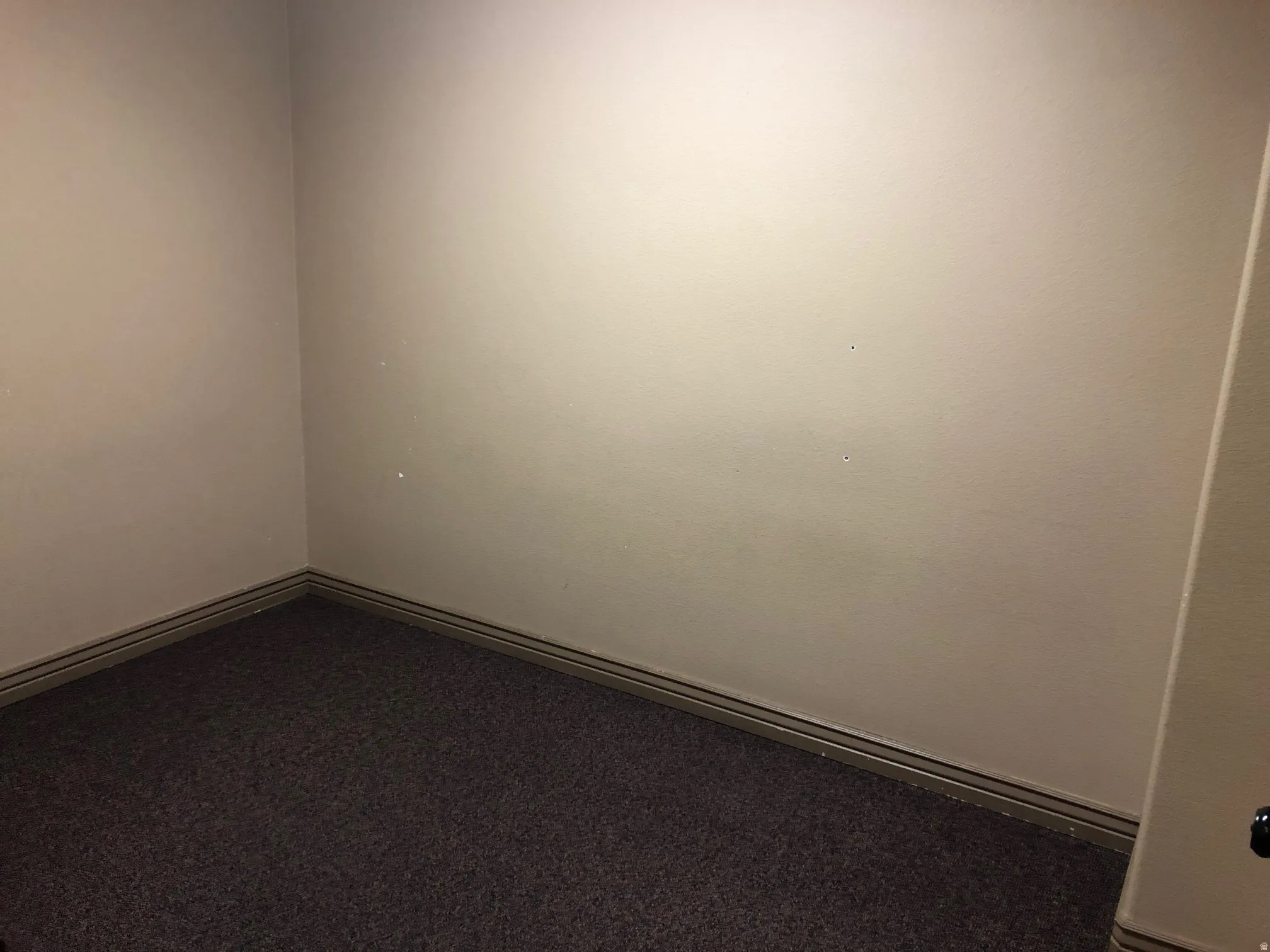 Unfurnished room featuring baseboards and dark carpet
