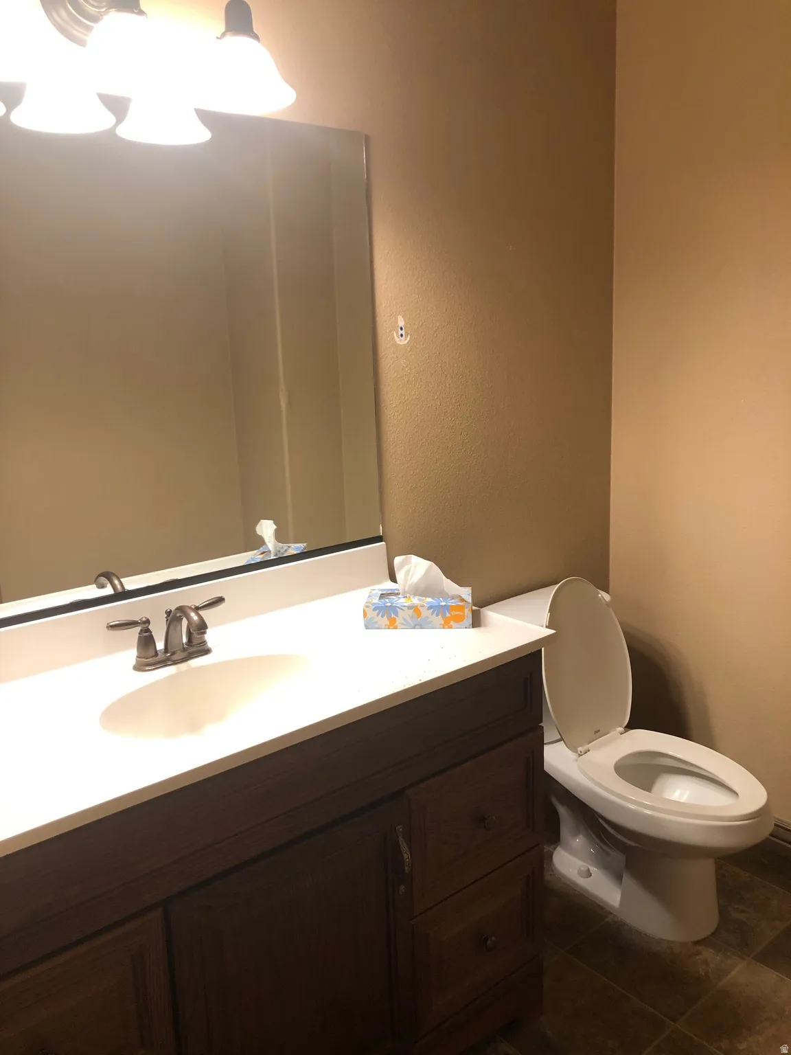 Half bath featuring vanity, dark tile patterned floors, and a textured wall