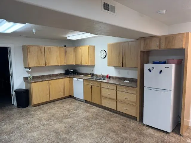 Kitchen featuring white appliances, dark countertops, and light flooring