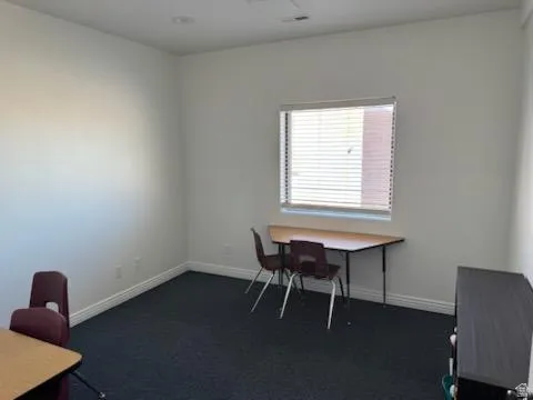 Office area with dark colored carpet and baseboards