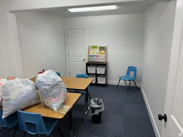 Office area with baseboards and dark colored carpet