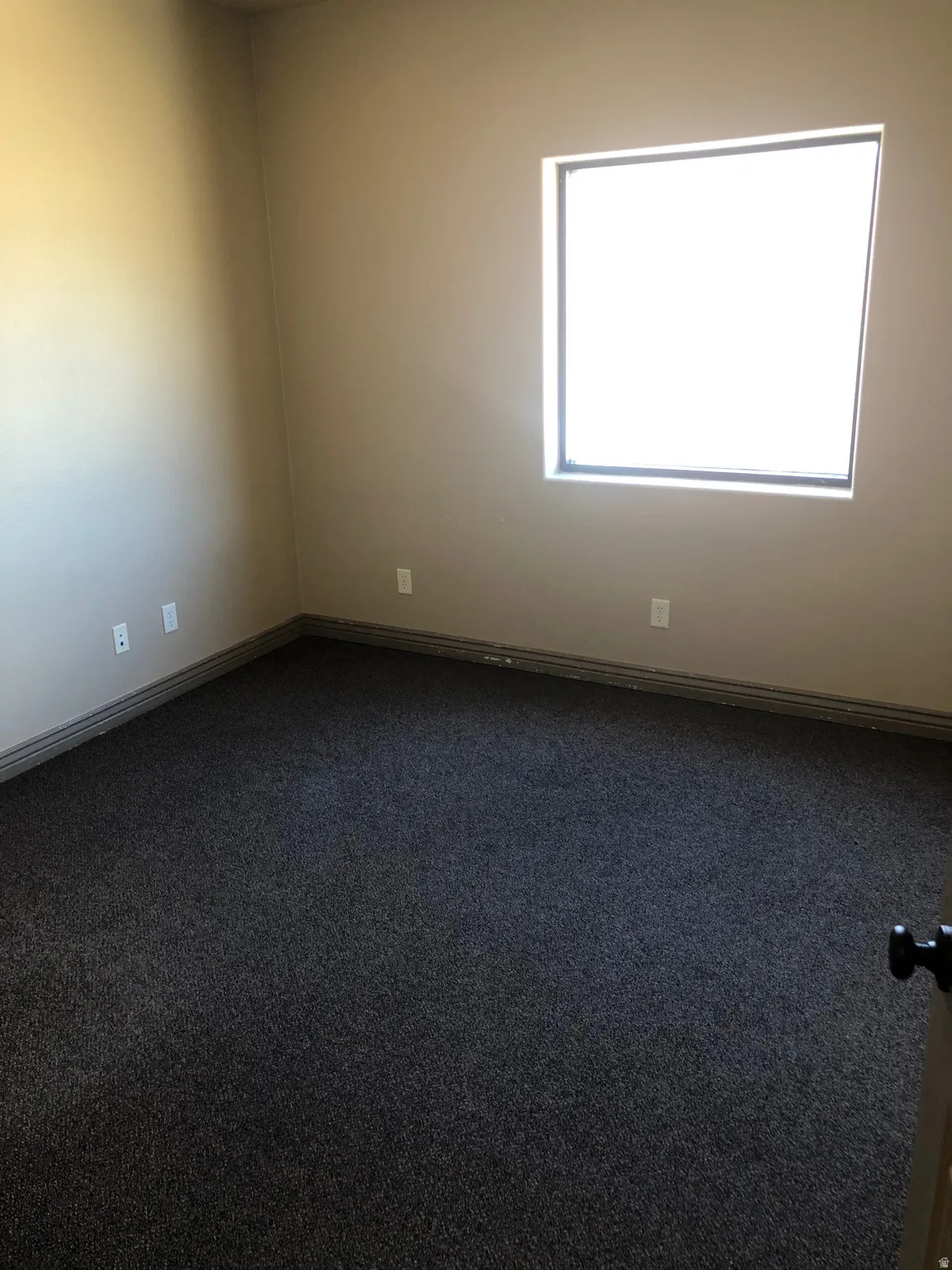Spare room with dark carpet and baseboards
