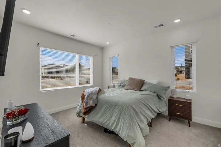 Bedroom featuring light carpet, multiple windows, and recessed lighting