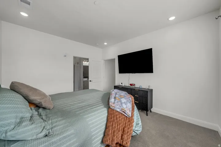 Carpeted bedroom with ensuite bath and recessed lighting