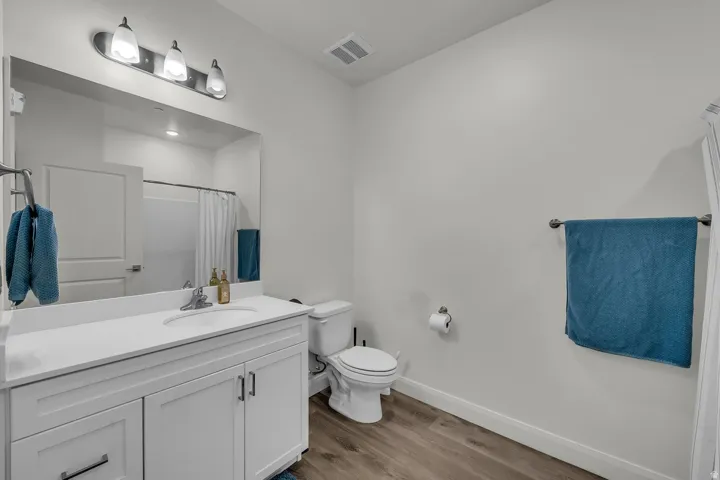 Bathroom with curtained shower, vanity, and light wood-style flooring