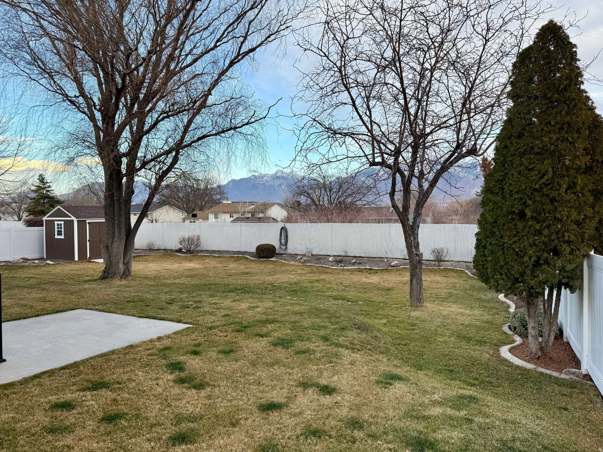 Fenced backyard featuring a storage unit, a patio, and a mountain view