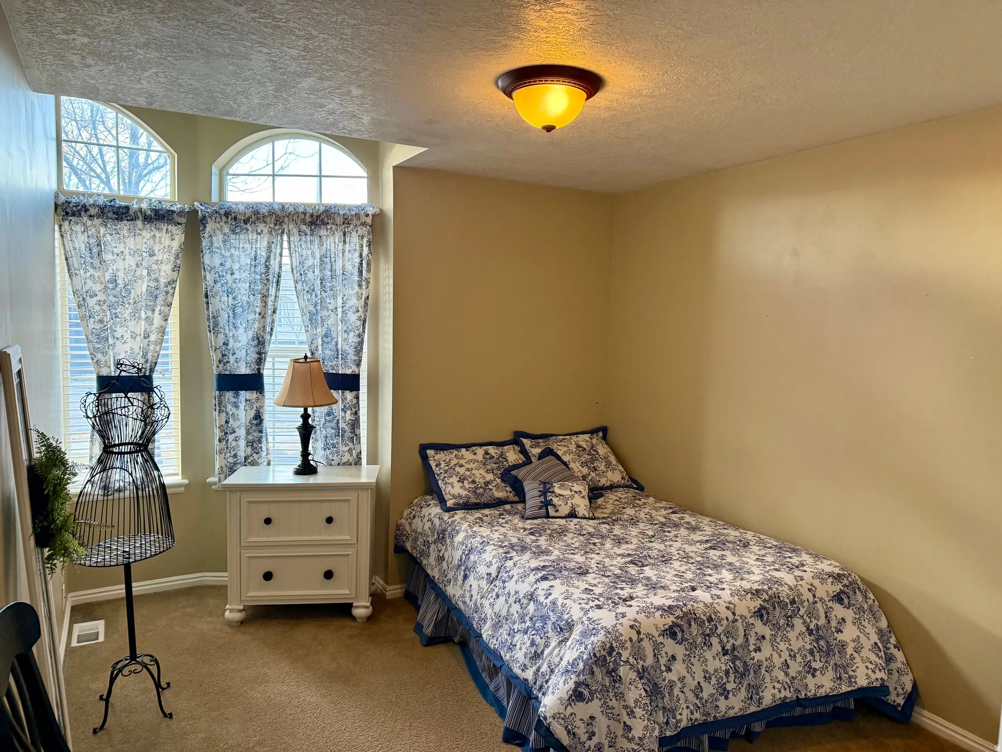 Carpeted bedroom with a textured ceiling and baseboards