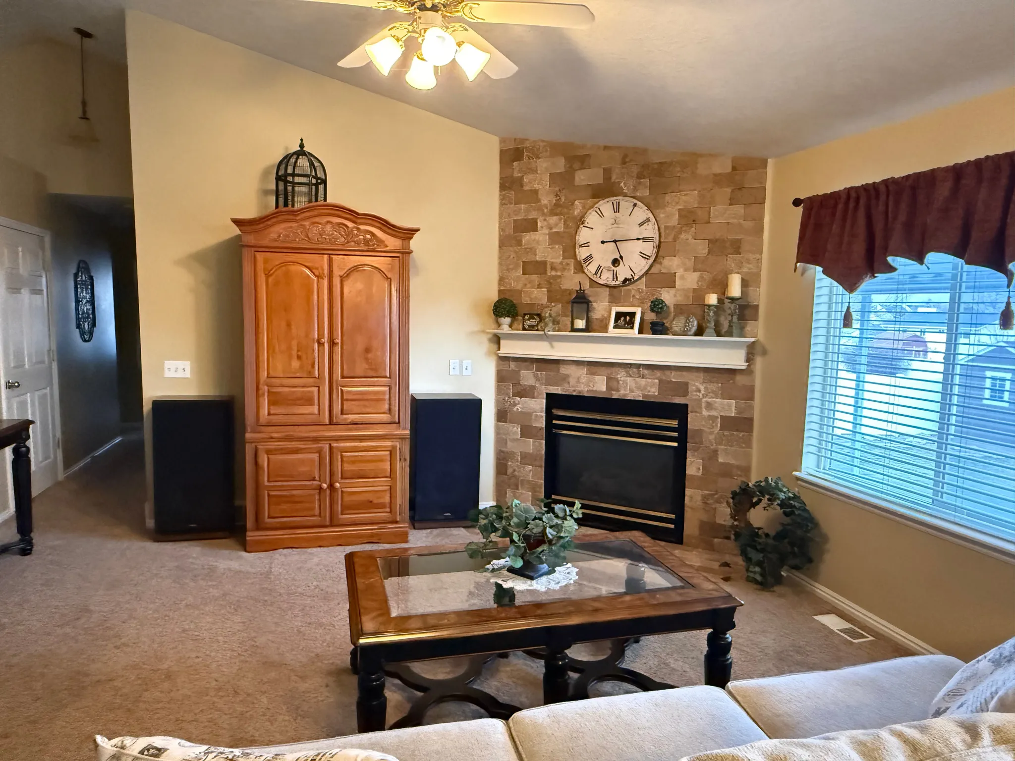 Living room featuring lofted ceiling, carpet floors, ceiling fan, and a fireplace