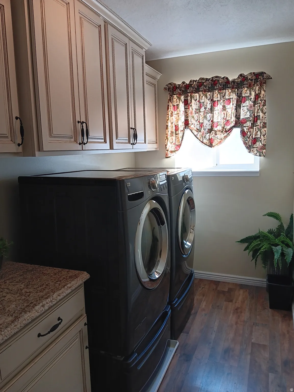 Laundry room featuring dark wood-style floors, cabinet space, and washing machine and dryer