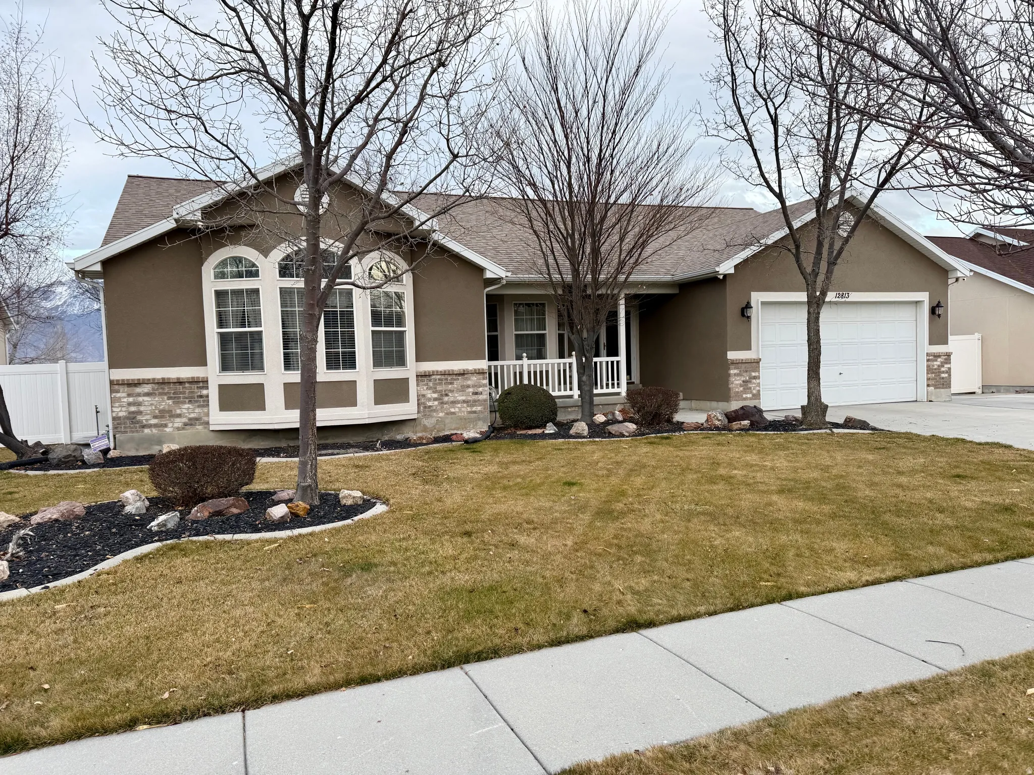 Single story home featuring stucco siding, a garage, driveway, and brick siding