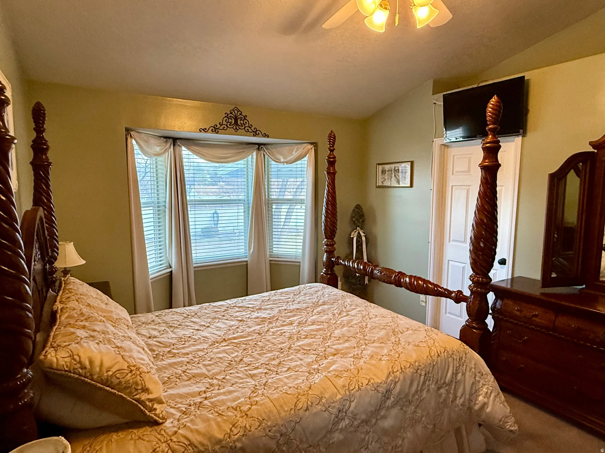 Carpeted bedroom featuring a ceiling fan and vaulted ceiling
