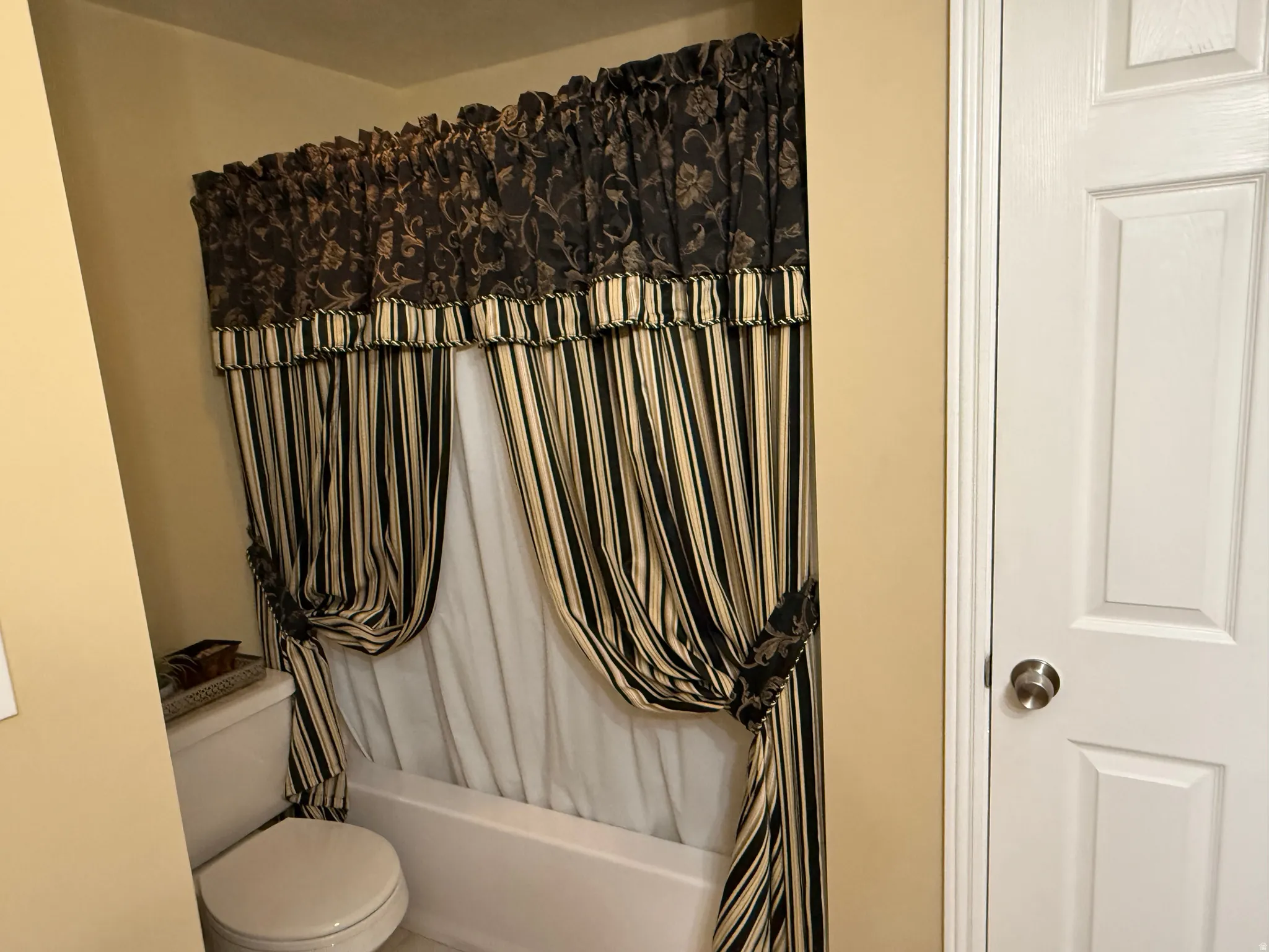 Bathroom with shower / bath combination with curtain and toilet