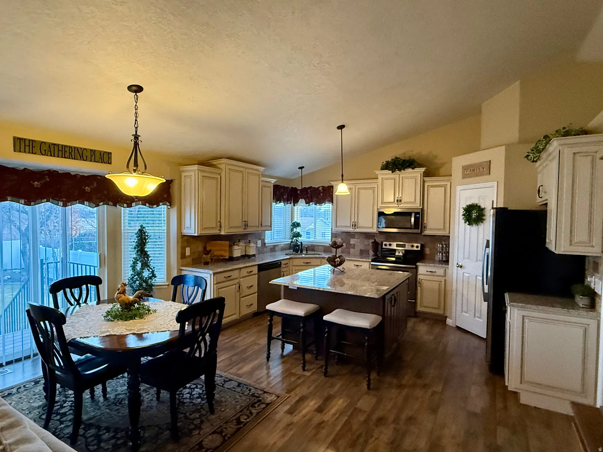 Kitchen with a center island, pendant lighting, dark wood-style flooring, a kitchen bar, and stainless steel appliances
