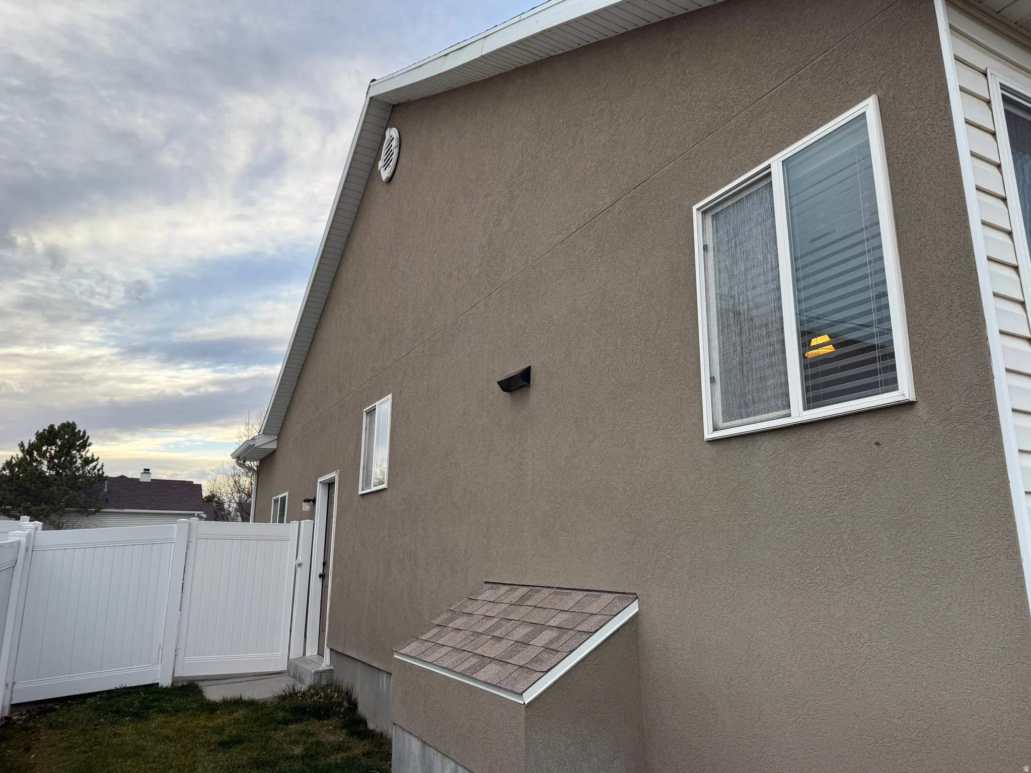 View of side of property with stucco siding and a gate