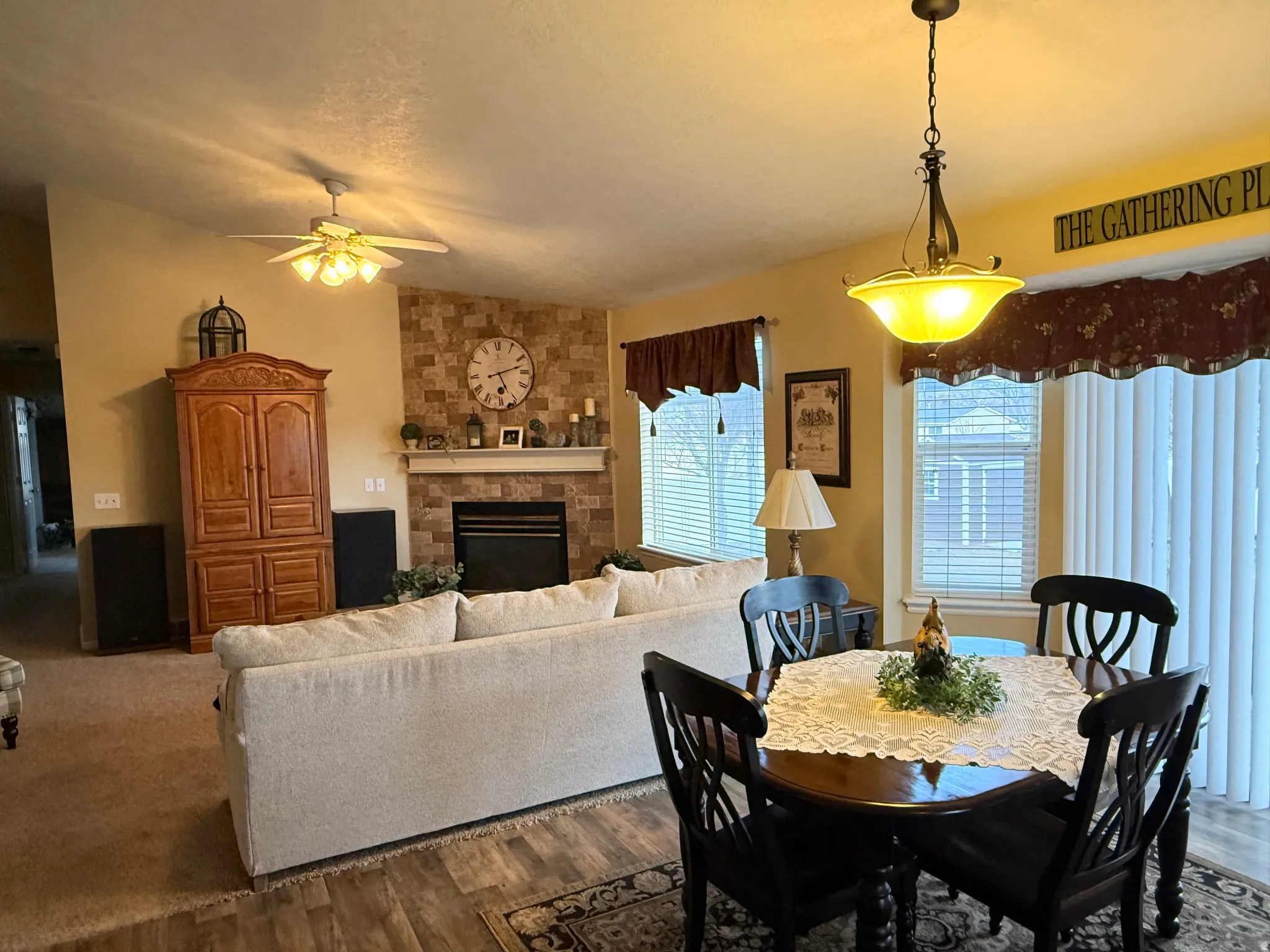 Dining room with a stone fireplace, dark wood finished floors, ceiling fan, and a textured ceiling