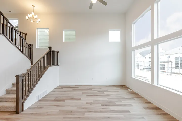 Two-story entry featuring light wood-finish flooring, a carpeted staircase with dark wood newel posts and balusters, and a contemporary multi-arm chandelier