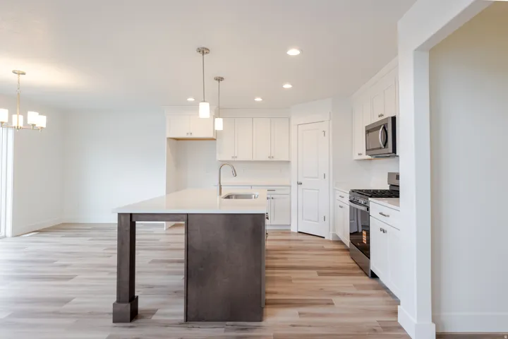 Kitchen featuring a central island with a contrasting base, light-toned wood-finish flooring, white cabinetry, stainless steel appliances, and recessed lighting