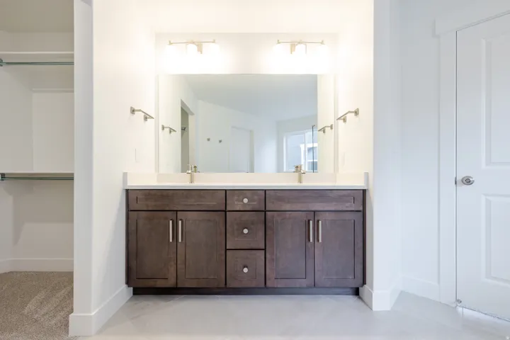 Dual vanity with dark wood-finish cabinetry, white countertop, and brushed nickel hardware