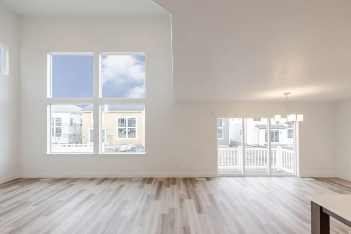Two-story great room with high ceilings, wood-finish flooring, and large multi-pane windows