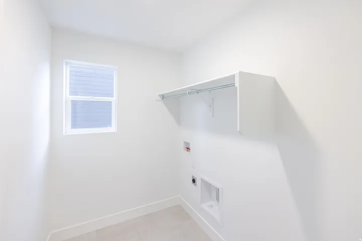 Laundry area featuring a window, overhead shelving, and a hanging rod